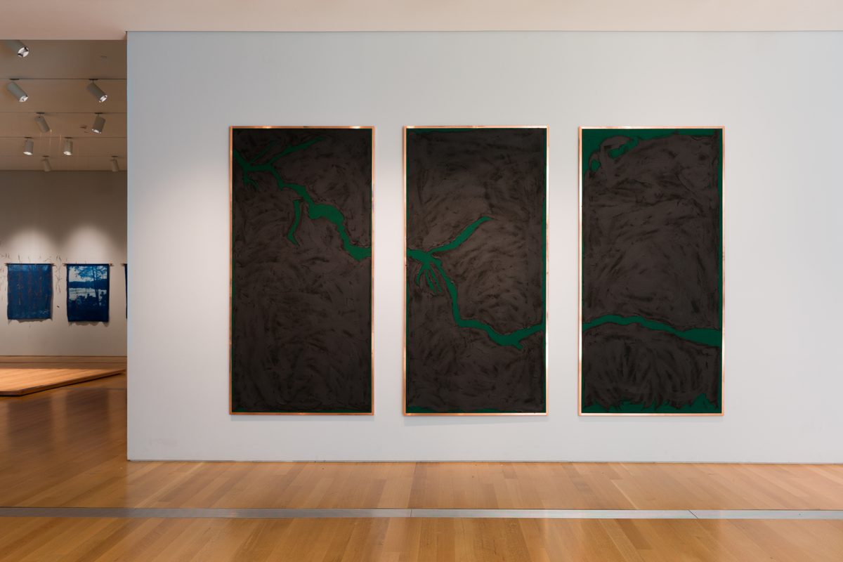 Three paintings in a set on an exhibit wall