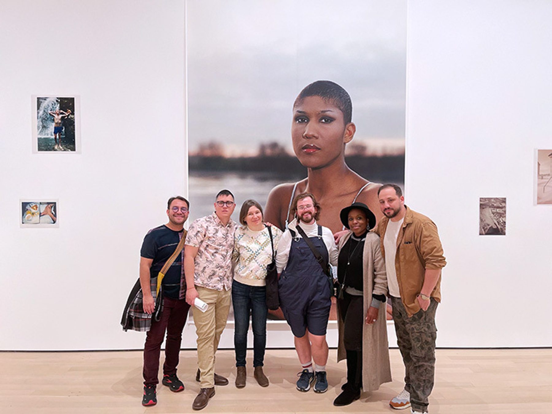 MFA students and Nzingah Oyo stand in front of a large photograph at the Museum of Modern Art.