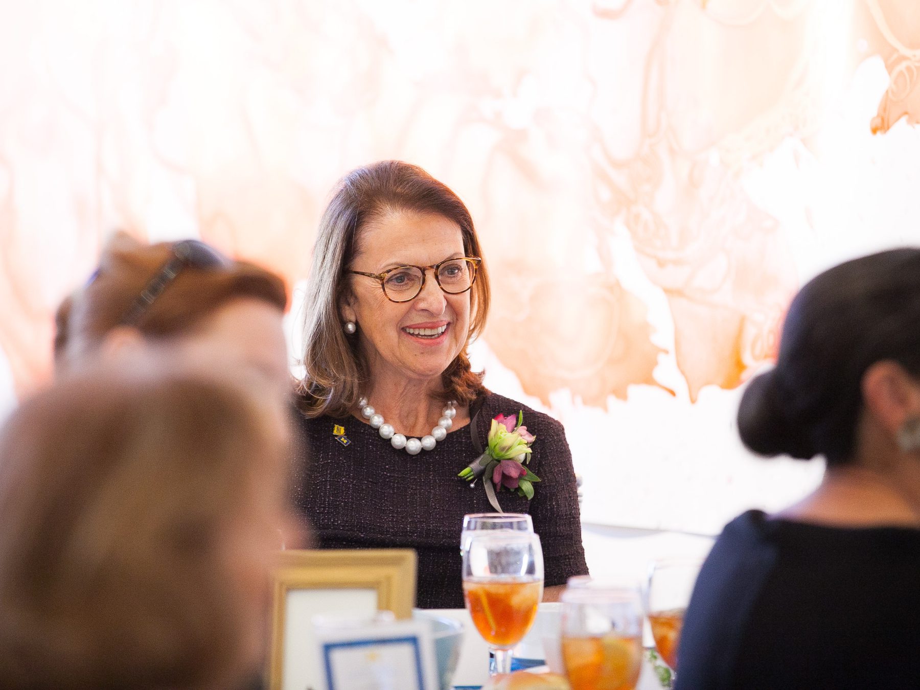 Penny Stamps sits at a table surrounded by guests at the Stamps School Naming Celebration