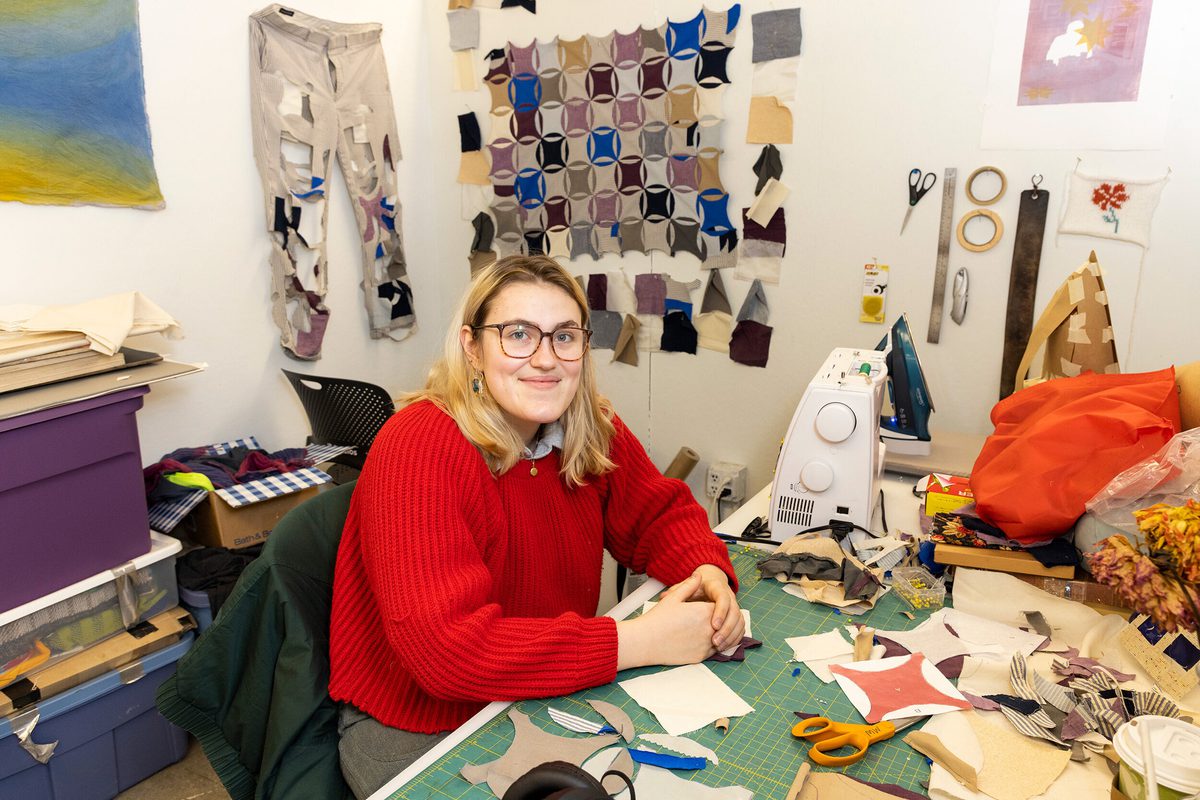 Maggie Wiebe, wearing a red sweater, works in Stamps studios