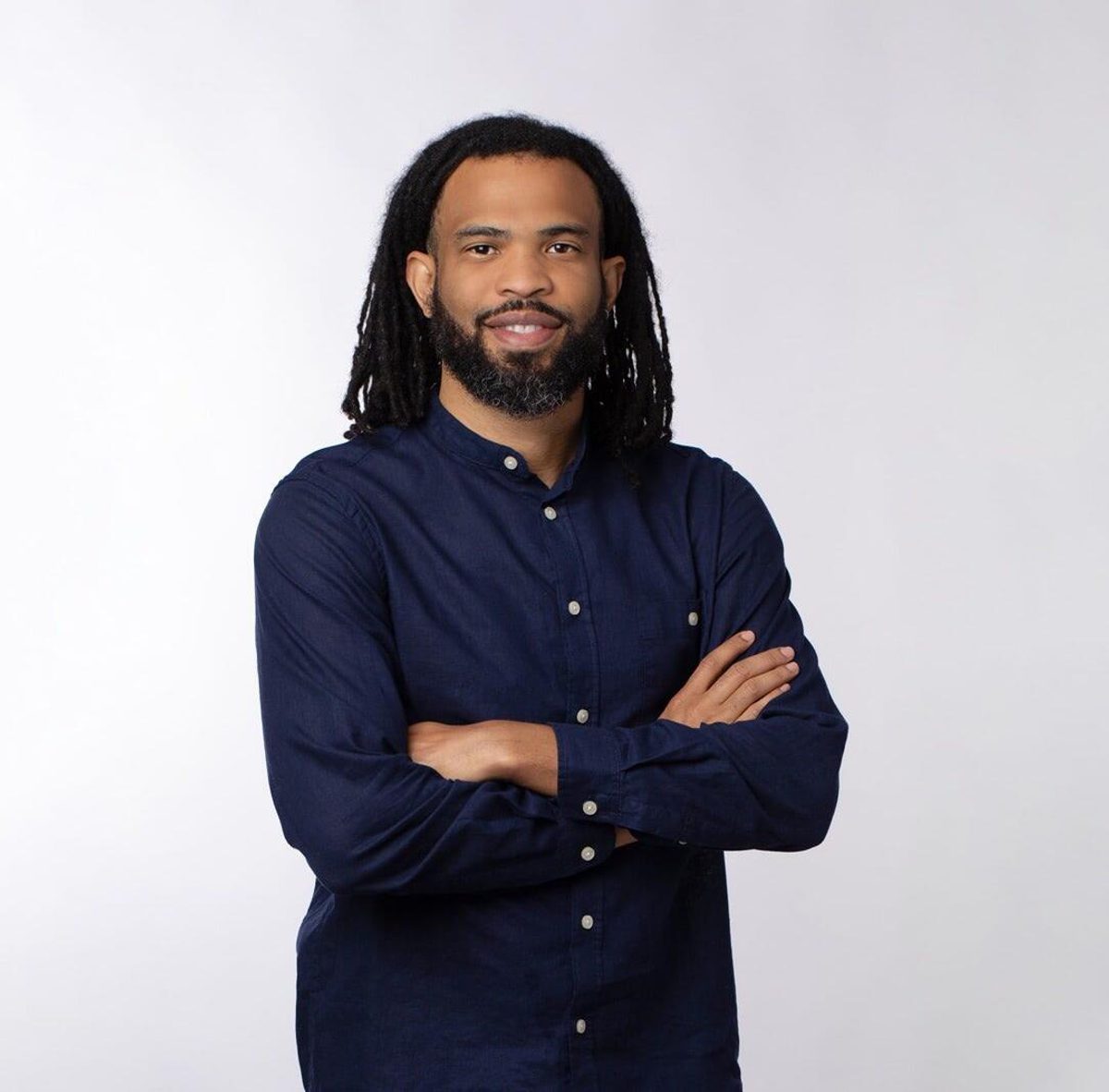 Cosmo Whyte stands with arms crossed wearing a dark button-down shirt