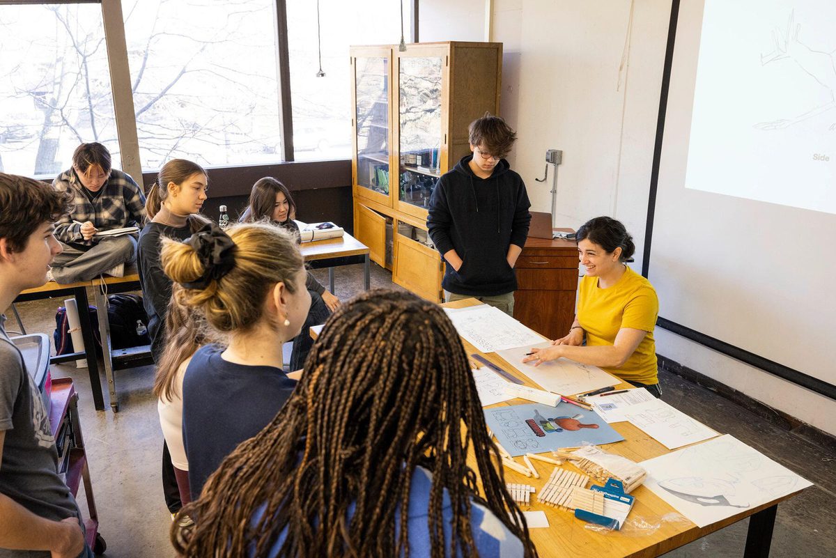 Students gather around a faculty member teaching a drawing class