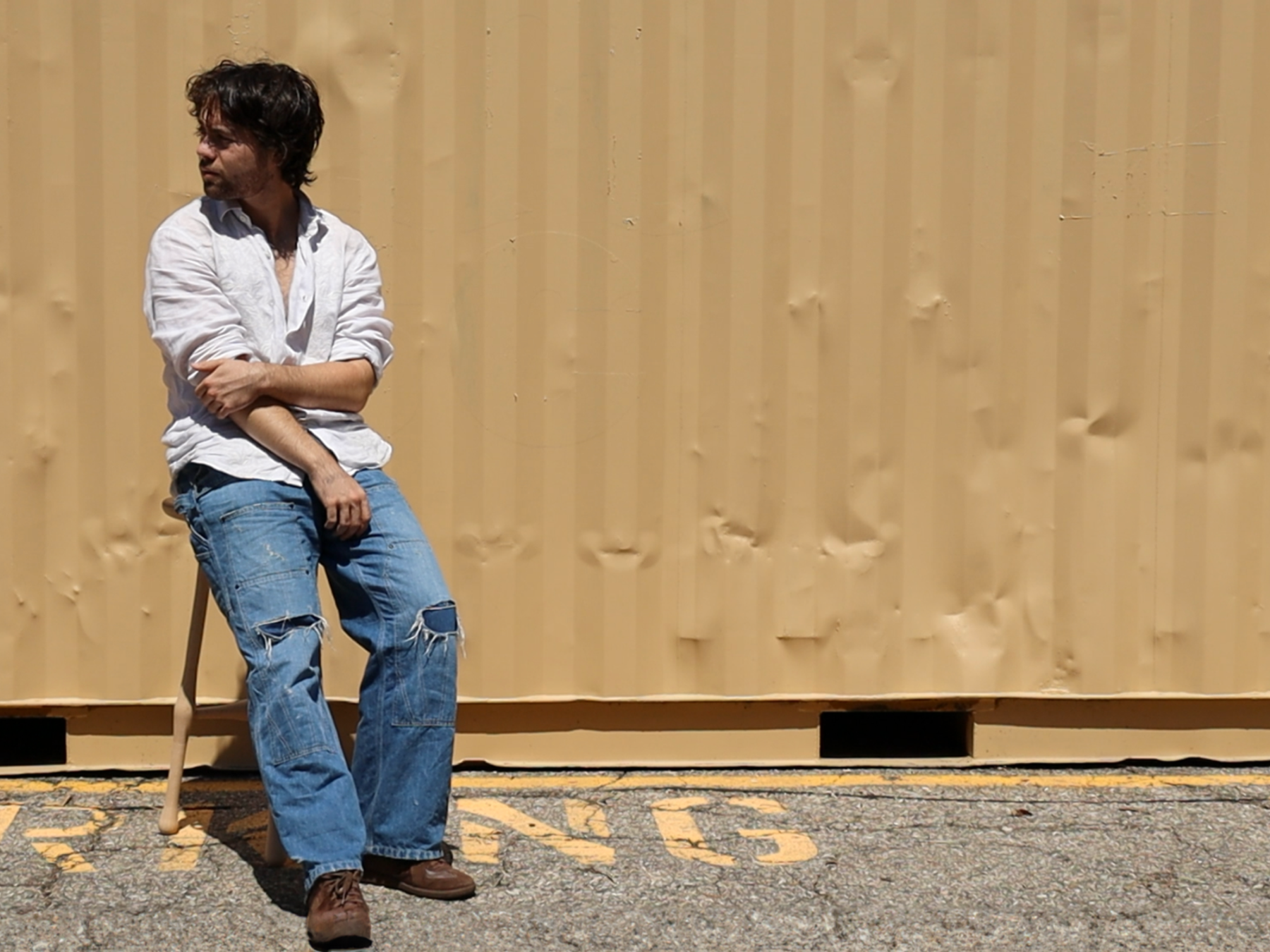Ben Michalsky poses for a portrait on a wooden stool.