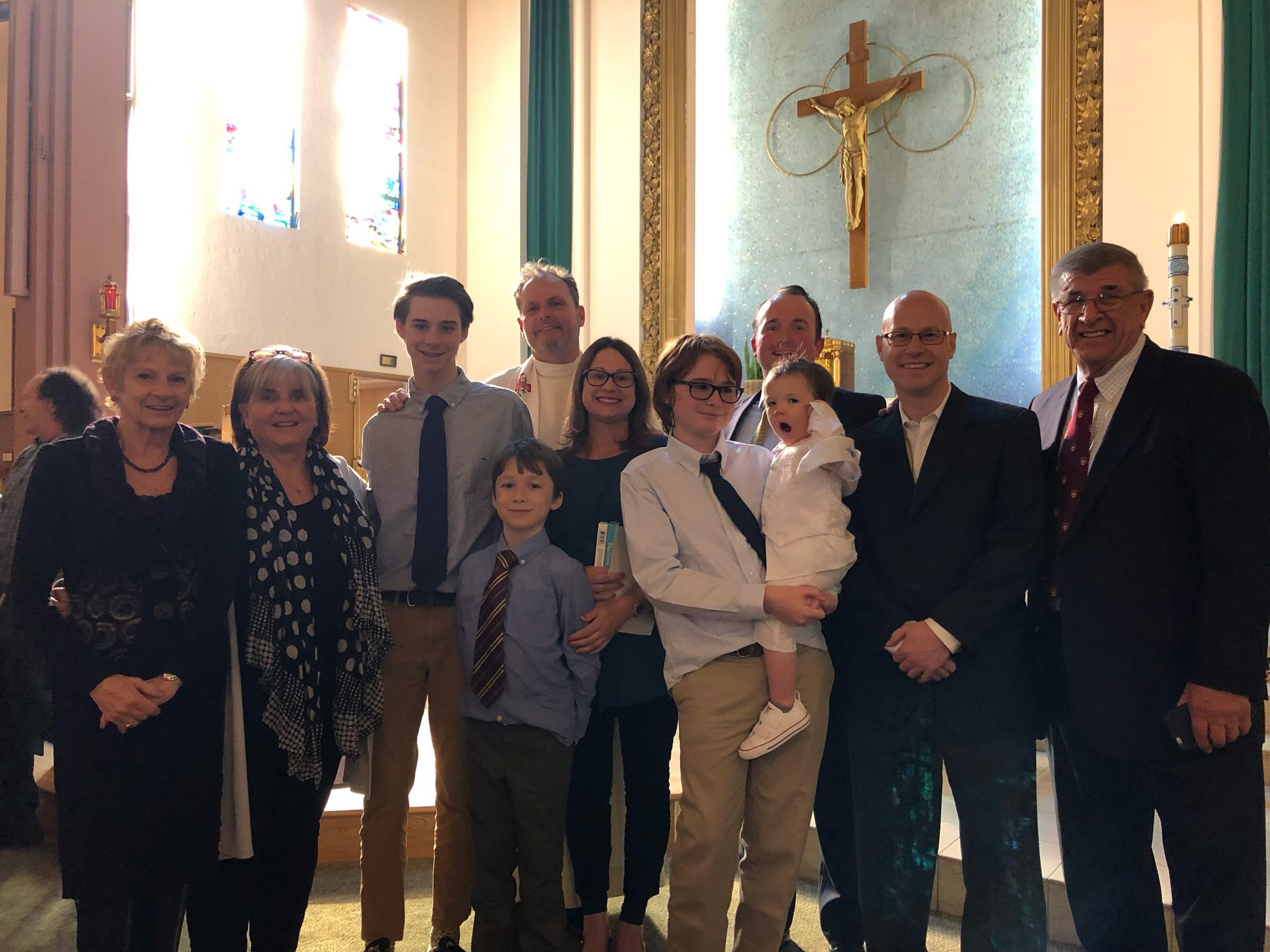 Eleven family members, including Jake Schraga and his Poppy, pose together in a church.